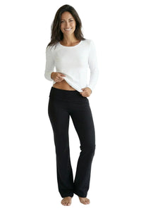 Woman wearing black lounge pants and white long sleeve tee, barefoot on white background