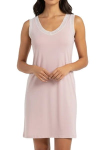 Woman wearing a light pink nightgown with lace trim on a white background