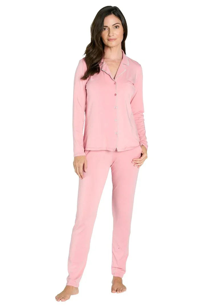 Woman wearing light pink long sleeve button-up pajama set with pants, standing barefoot