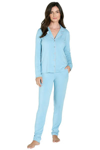 Woman wearing light blue long-sleeve button-up pajama set with pants, barefoot