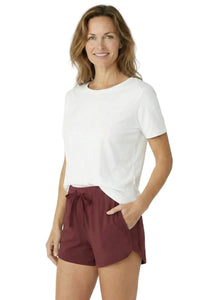 Woman wearing soft white loungewear tee and burgundy sleep shorts with pockets