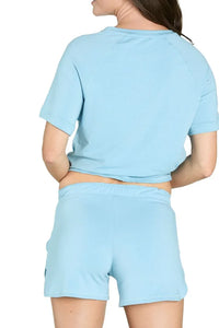 Woman wearing light blue short-sleeve loungewear set with shorts, viewed from the back