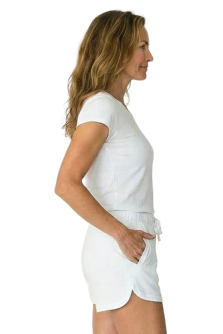 Woman in white Pima cotton loungewear sleepwear set, side view, hands in shorts pockets