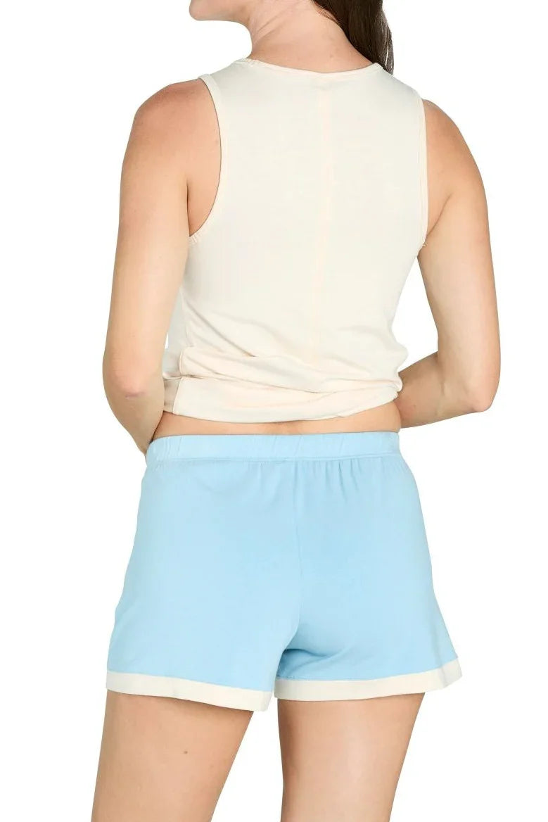 Woman wearing sleeveless cream top and sky blue lounge shorts, back view