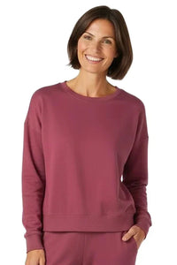Woman wearing rosewood Pima cotton loungewear sweatshirt and matching pants, smiling