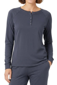 Woman wearing a steel blue long-sleeve henley shirt and pants on a white background