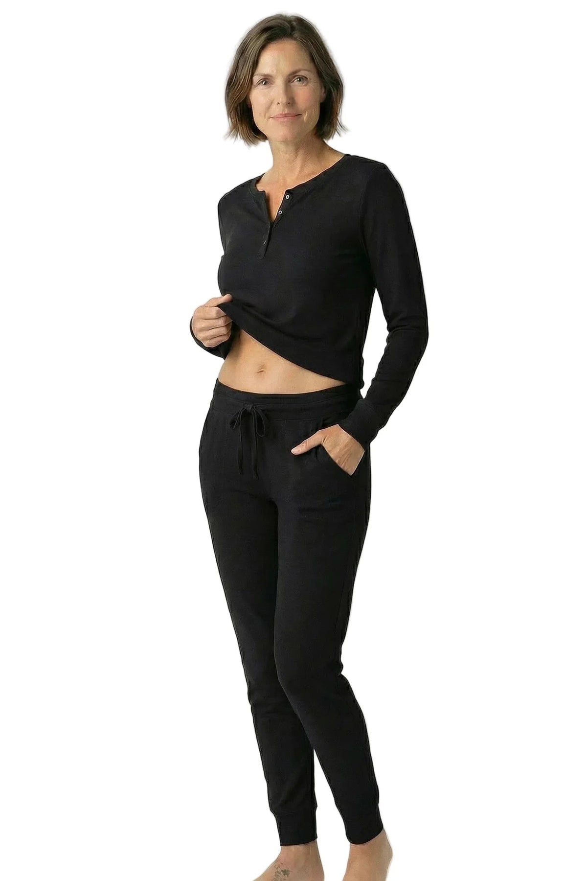 Woman wearing black long sleeve loungewear set with jogger pants, barefoot, on white background
