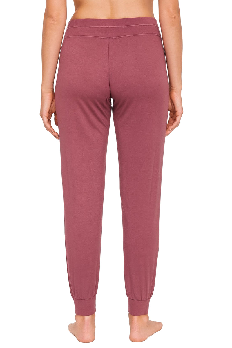 Rearview of rosewood colored joggers worn by a woman on a white background