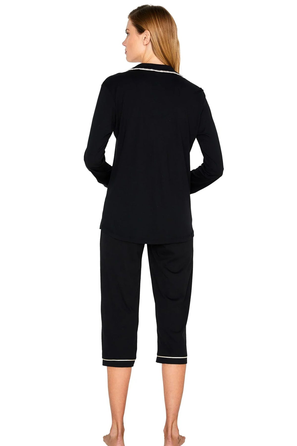 Woman wearing black long sleeve loungewear set with white trim, shown from the back