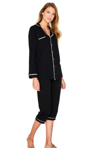 Woman wearing black long sleeve Pima cotton pajama set with white trim, cropped pants