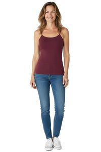 Smiling woman wearing a Bordeaux-color spaghetti strap tank top with blue jeans and white sneakers