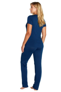 Woman wearing navy blue short sleeve top and matching lounge pants, standing barefoot facing away