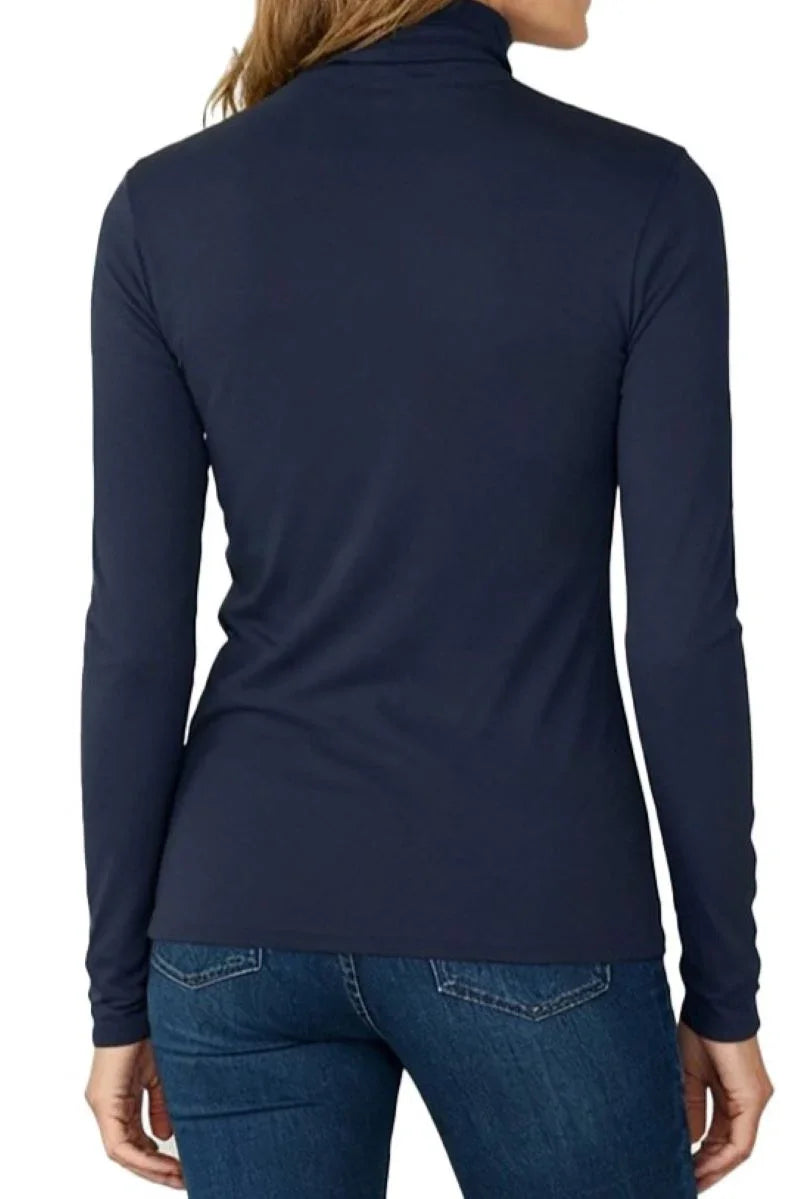 Back view of woman wearing midnight blue long sleeve turtleneck and blue jeans