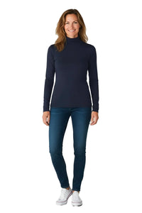 Smiling woman wearing a midnight blue turtleneck sweater, dark blue skinny jeans, and white sneakers on white background