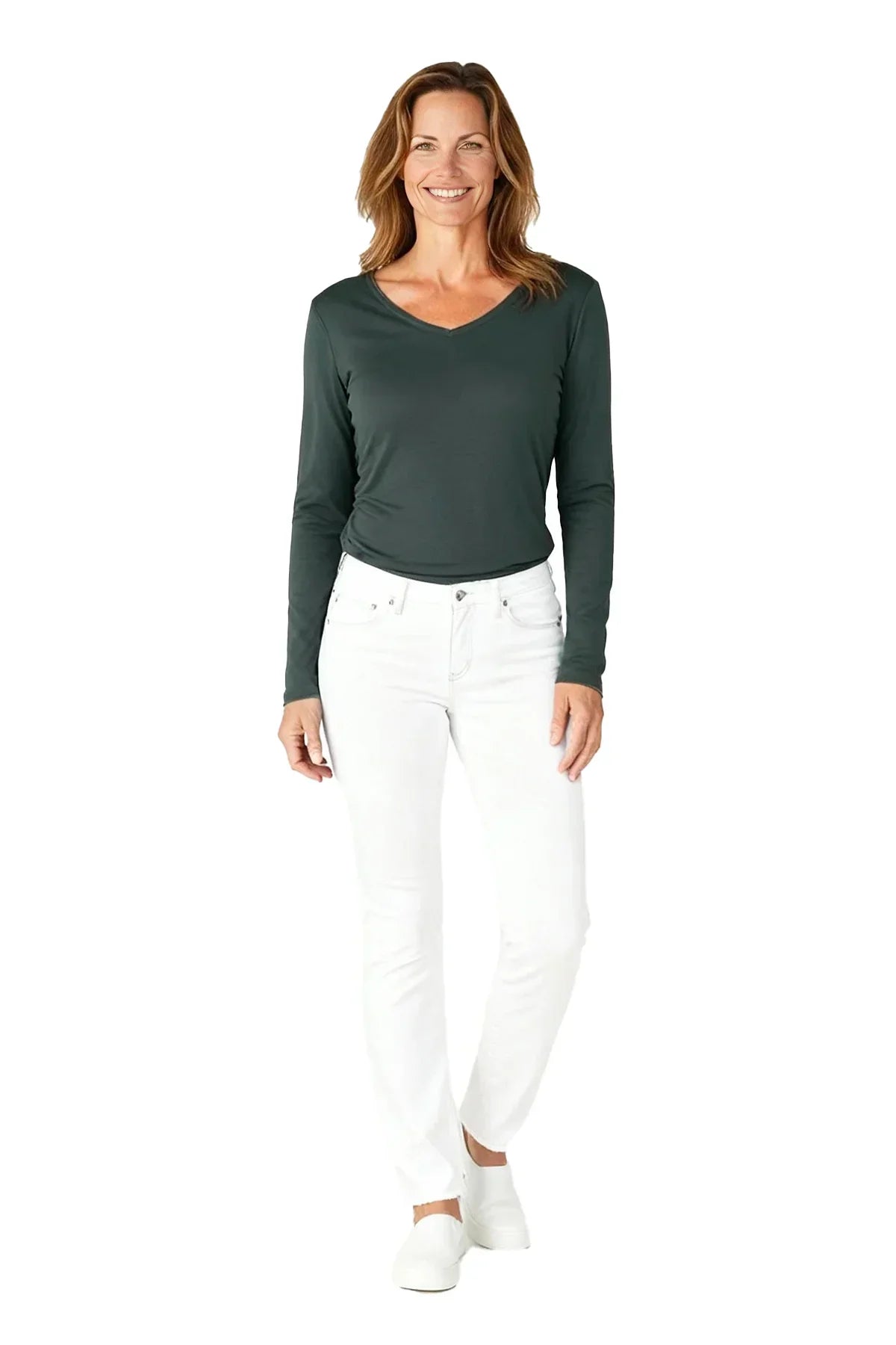 Smiling woman wearing spruce green long sleeve V-neck shirt with white jeans and white slip-on shoes