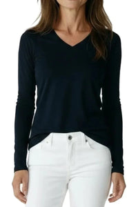 Woman wearing black long-sleeve V-neck shirt tucked into white pants