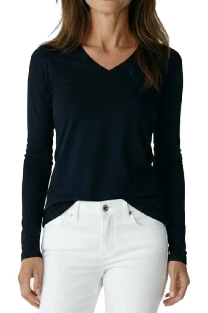 Woman wearing black long-sleeve V-neck shirt tucked into white pants