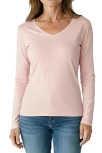 Woman wearing a shell pink long-sleeve V-neck shirt with blue jeans