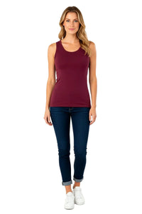 Woman wearing a fitted bordeaux tank top with dark blue cuffed skinny jeans and white sneakers