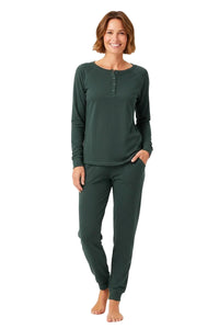 Smiling woman wearing dark green long-sleeve top and matching jogger pants lounge set barefoot