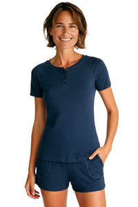Smiling woman wearing steel blue short sleeve henley top and matching shorts on white background